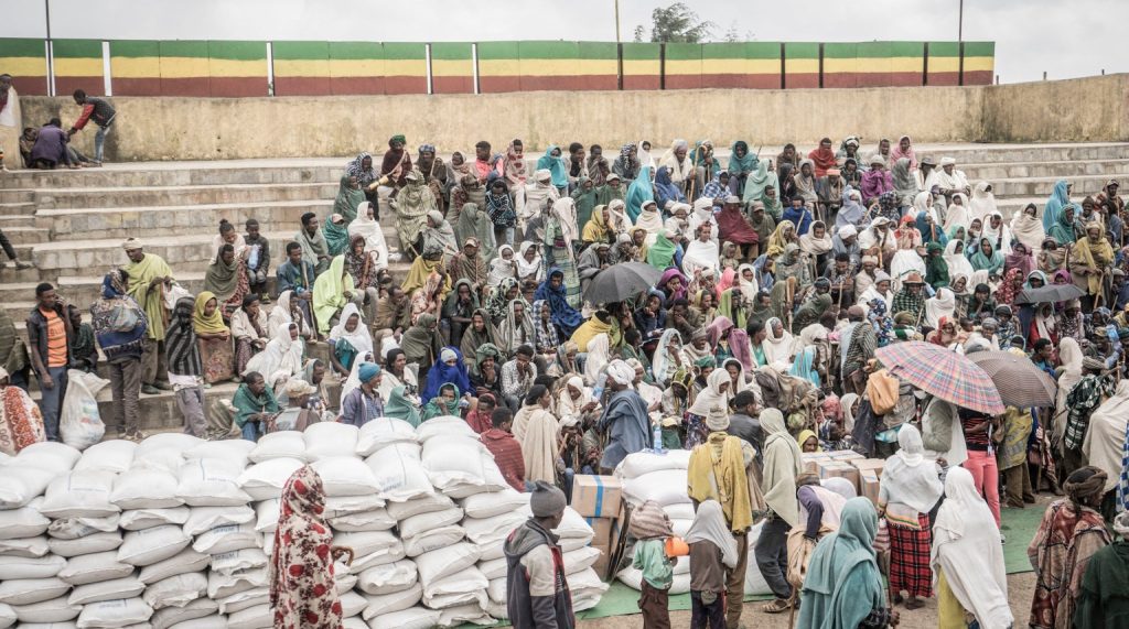 Le persone fuggite dalla guerra di May Tsemre, Addi Arkay e Zarima si riuniscono in un campo per sfollati interno allestito temporaneamente per ricevere i primi sacchi di grano dal Programma alimentare mondiale a Debark, a 90 km dalla città di Gondar, in Etiopia, il 15 settembre 2021. (Foto: Amanuel Sileshi / AFP)